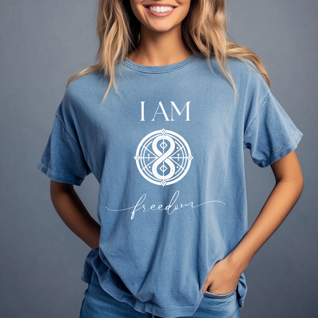 Model wearing a crew neck t-shirt with symbolic sigil centered on the chest, representing freedom. 
The shirt reads 'I AM' in block font above the symbol and 'freedom' in script font below.
Declare to the world: I AM Free.