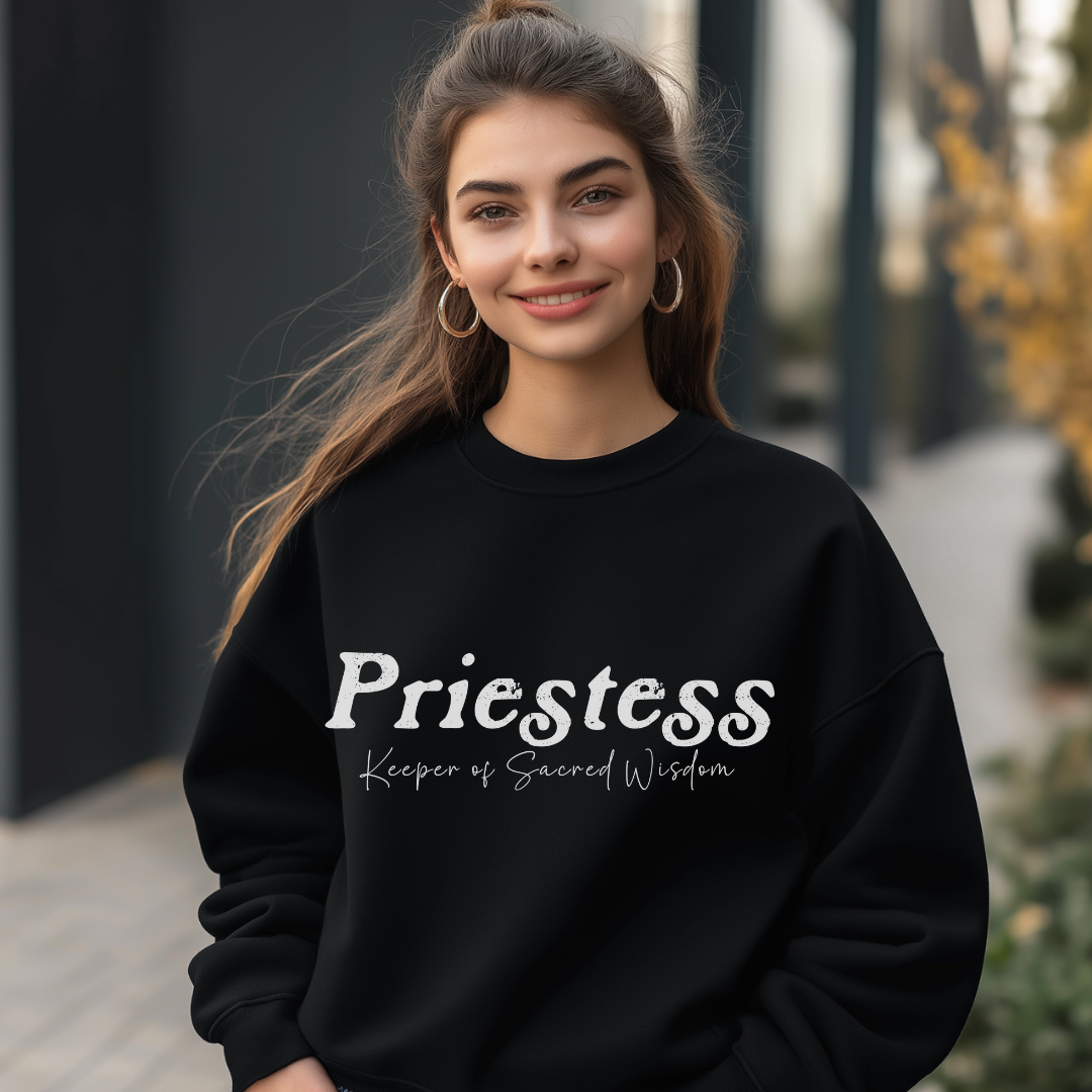 Model wearing a crew neck sweatshirt.
The sweatshirt says “Priestess” in distressed lettering across the chest with “Keeper of Sacred Wisdom” printed in smaller scripted lettering underneath.
Wear, Embody, Be the Priestess.